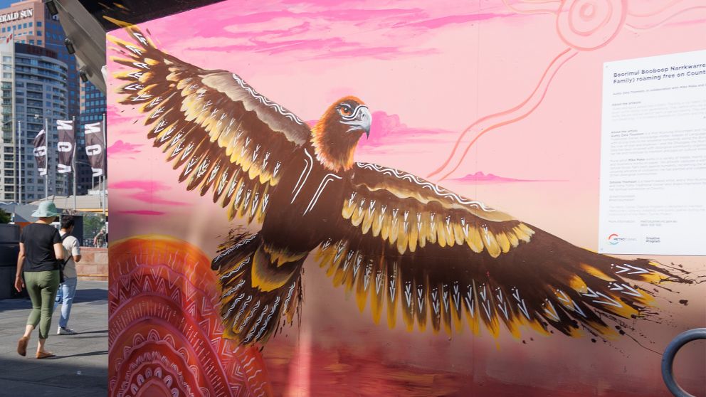 A large flying bird on a pink background is painted on a wall