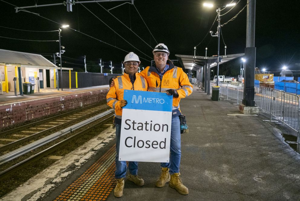 Crews hold 'Station Closed' sign after final train stops at Glenhuntly Station