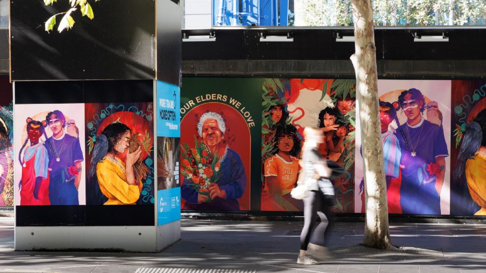 Image of a person walking past a colourful public artwork on a construction site hoarding 