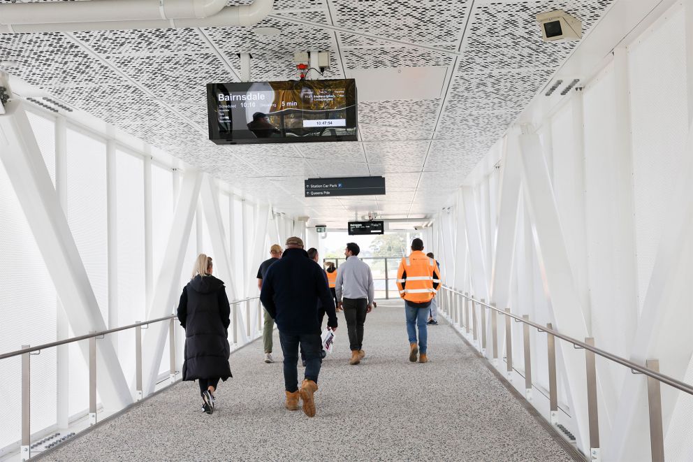 People walking through overpass and signage/screens