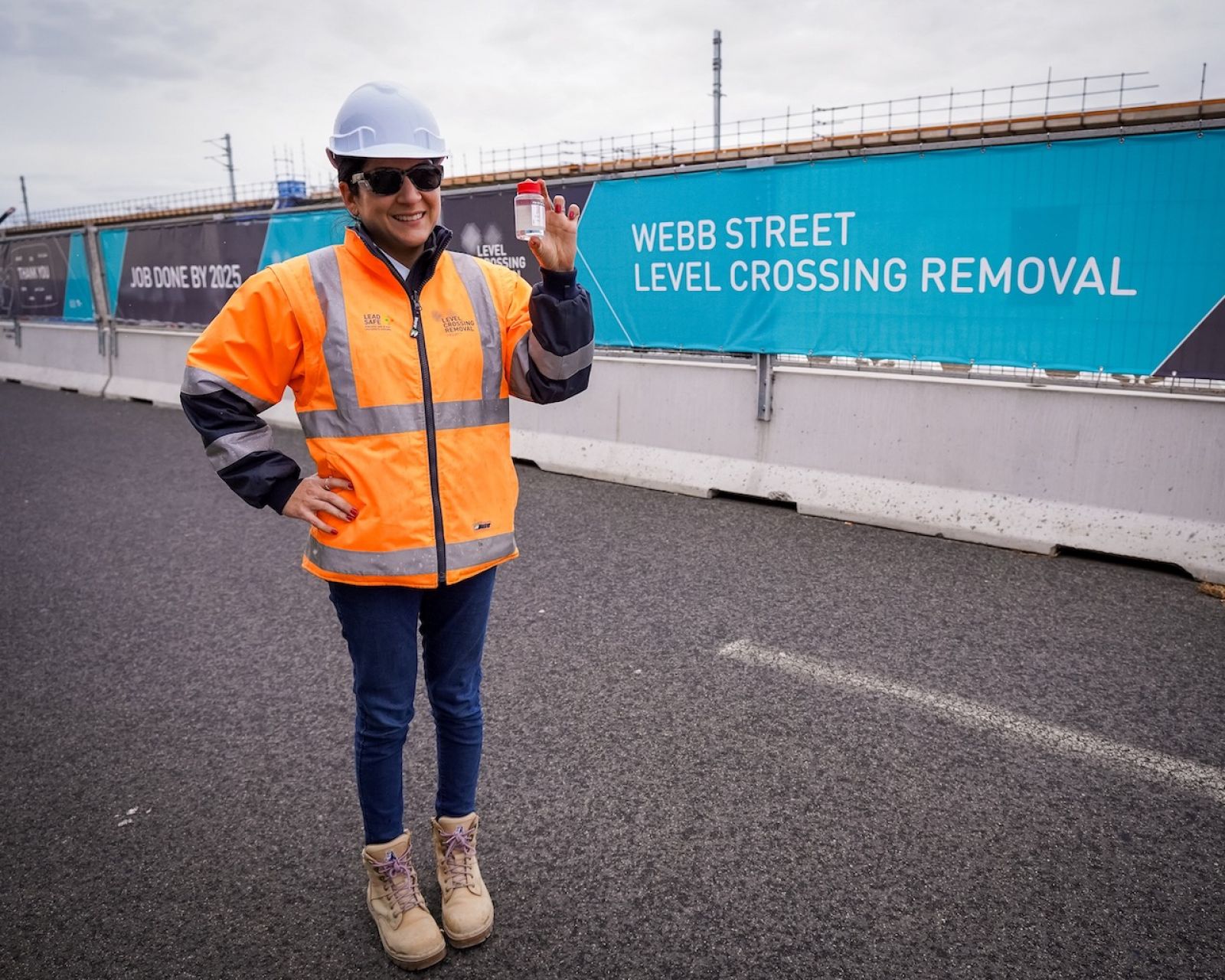 A worker stands in front of Webb Street Level Crossing Removal signage holding HVO
