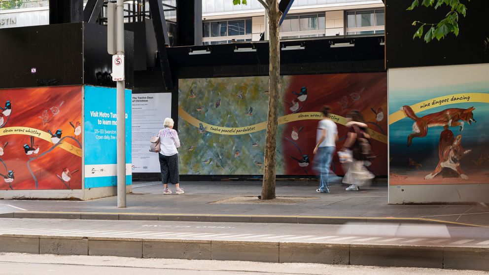 Colourful construction hoarding that features paintings of twelve peaceful pardalotes and eleven wrens whistling 