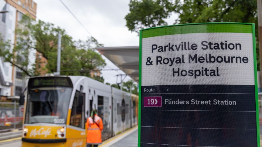 Parkville Station tram stop signage next to a tram boarding passengers