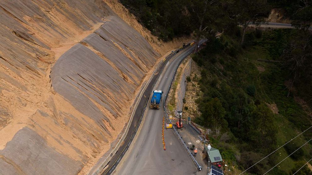 A water truck crosses face of the landslip