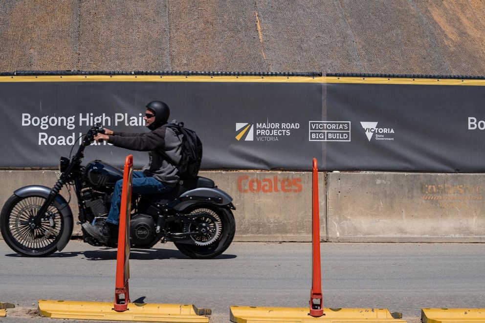 A motorbike rider passes across the front of the landslip on Bogong High Plains Road