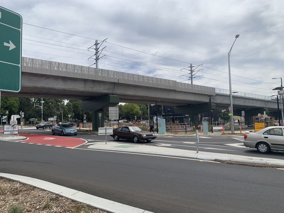 Three cars passing under the elevated rail bridge