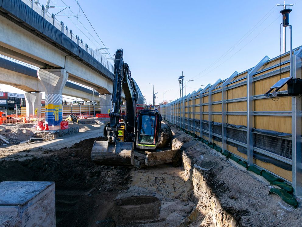 Excacator digging a tench within the boundary of the Clayton Construction site