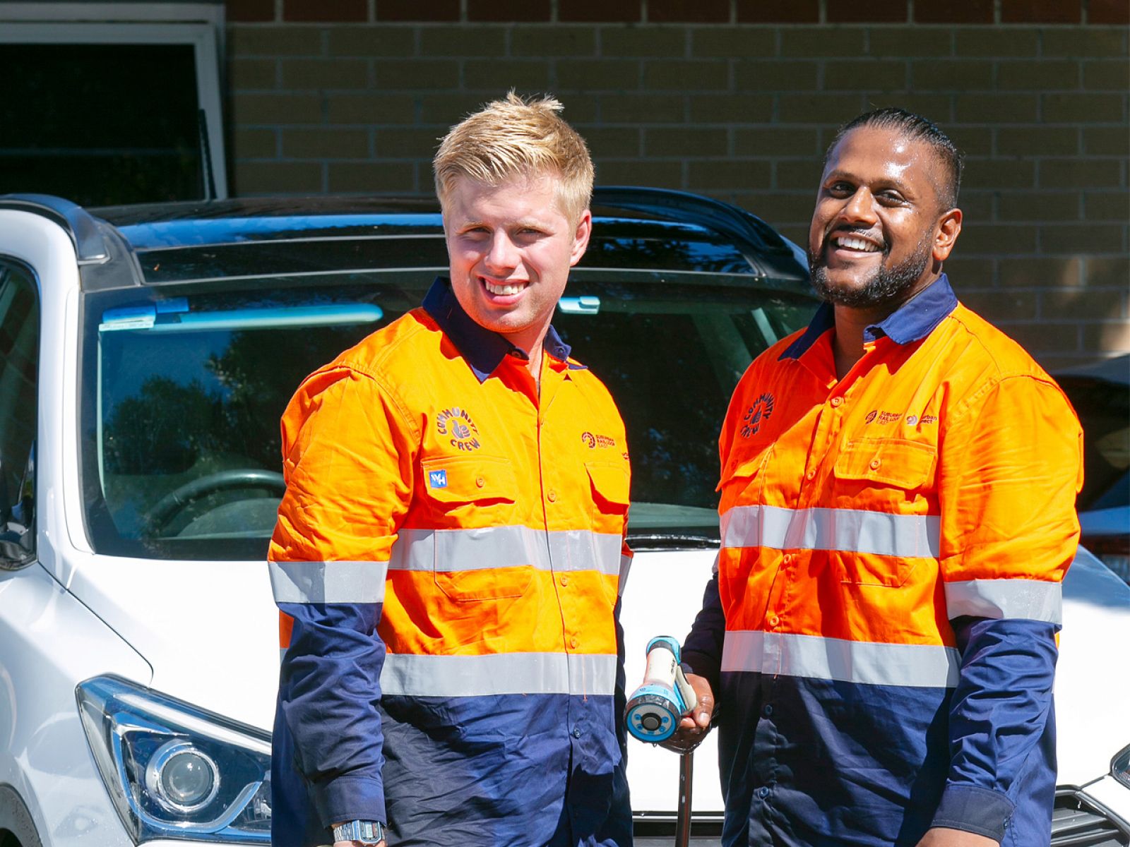 Two community crew members standing by a freshly washed car