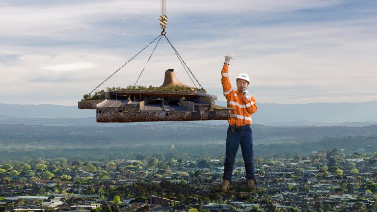 A giant construction worker moves a piece of road into place.