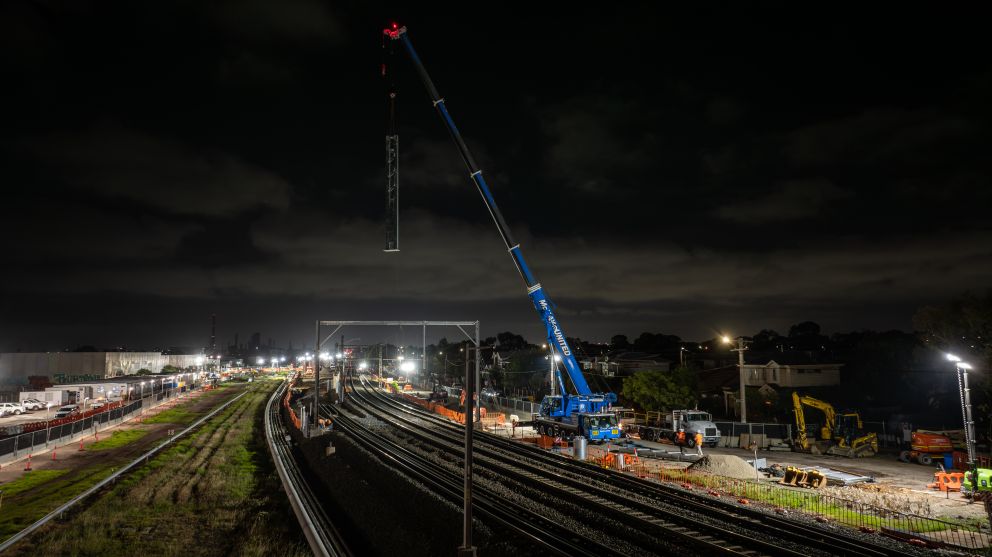 A mobile crane lifts out overhead electrical structures