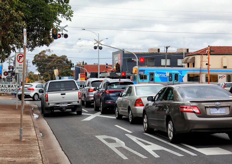 Cars and trucks wait at the boom gates at a level crossing