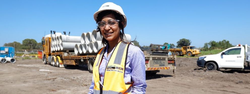 Woman in hard hat smiling at the camera on site