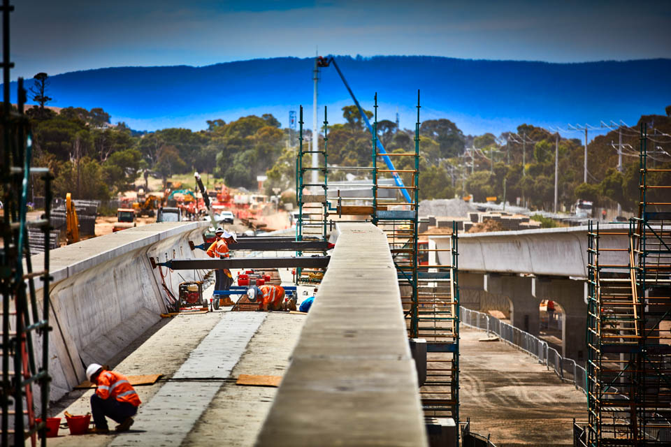 Construction workers work on large concrete structures, in a country setting.
