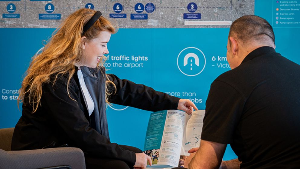 A woman holding an information sheet next to a man with his back to the camera 