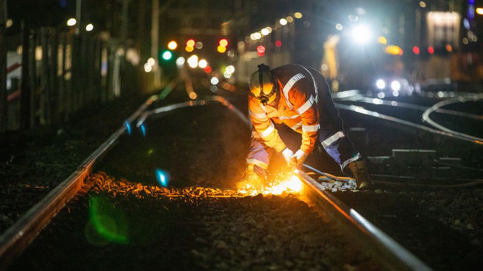 Worker welding rail tracks at night