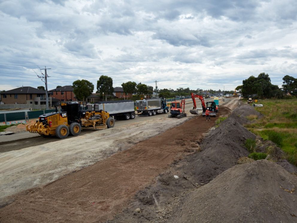 Image of excavators and trucks digging up and flattening earth