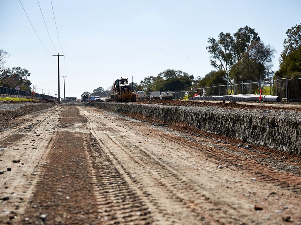 Image of a worksite cleared out to lay the road. The sides are lifted to prepare of paths etc.