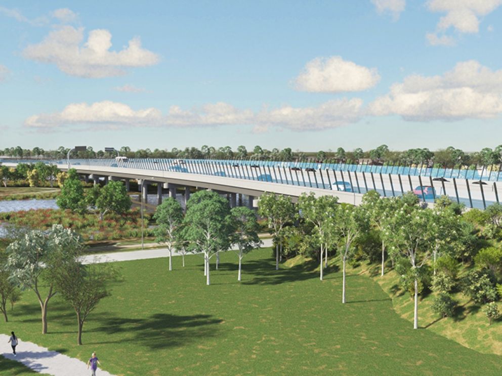 An artist impression of the bridge at Waterways. The bridge goes over a lake and has clear blue barriers on the bridge. The ground beneath the bridge has a walking/cycling path, grass and trees.