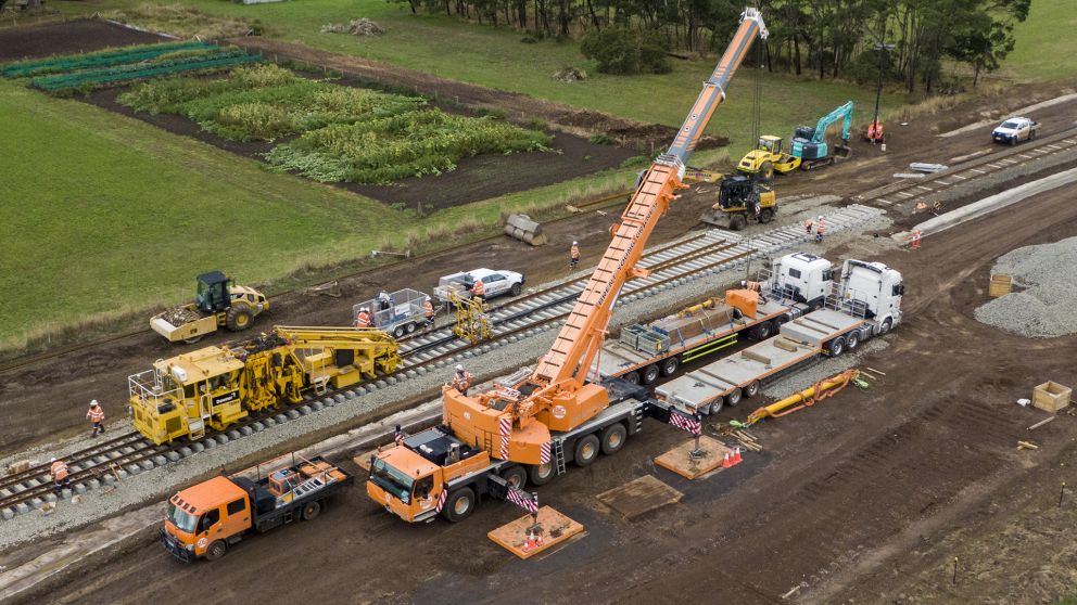 Birds eye view of track being built with workers around and a crane.