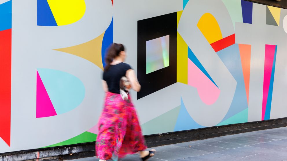 Close up of word ‘Best' on hoardings artworks. Coloured shapes are seen inside and outside letters. 