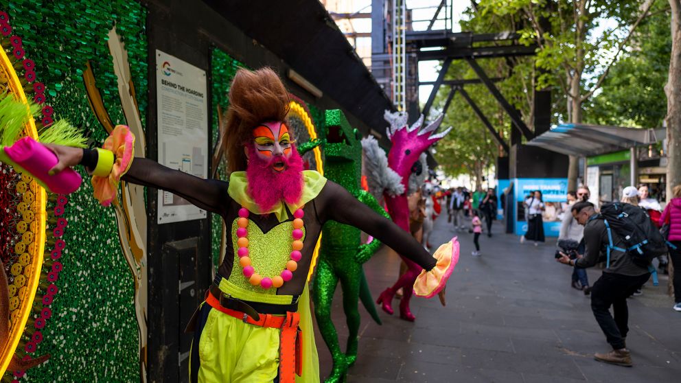 A performer in fluorescent colours walks down a Melbourne city street