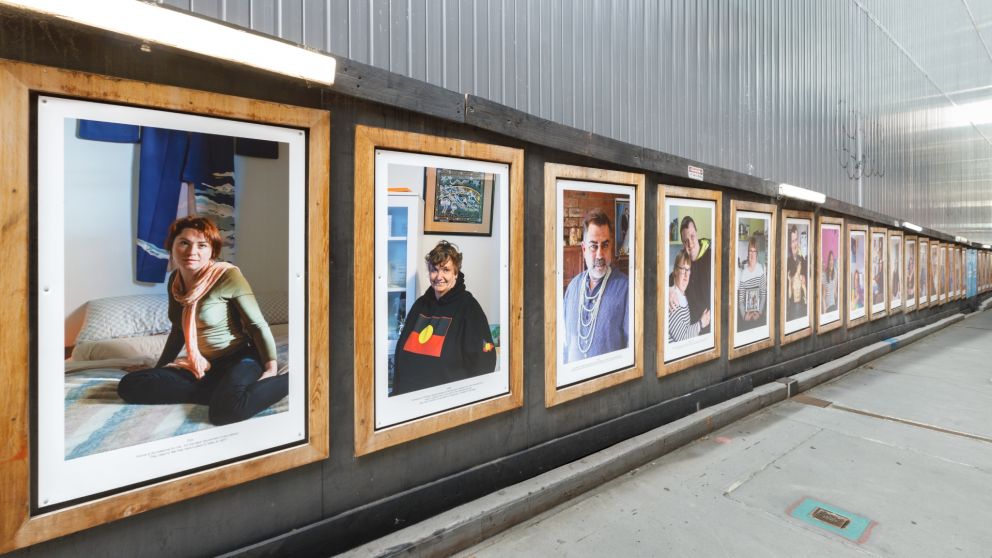 Portrait photos of different people on a hoarding wall inside wooden frames