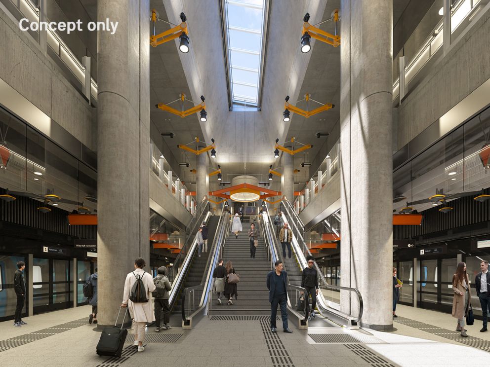 Render of the inside of Arden Station from the point of view of the platform with trains on the left and right, looking up to the escalators and the skylight in the middle