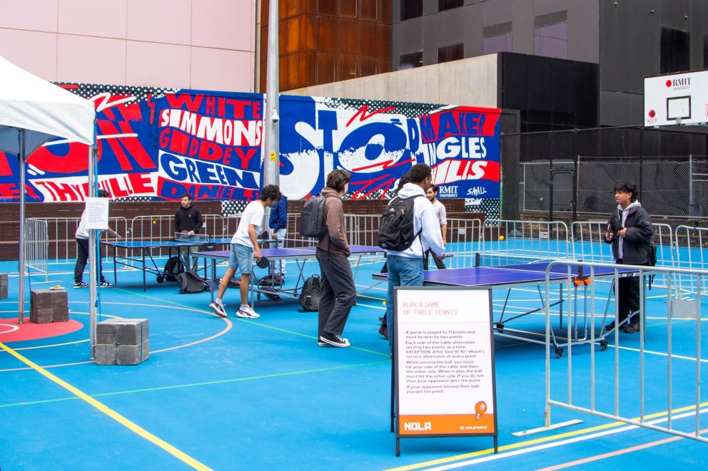 Image of three blue table tennis tables with people playing table tennis at each table. 