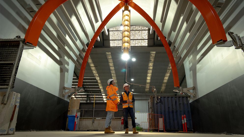 Two people in hi vis looking up at Metro Tunnel architectural elements in the flower market warehouse