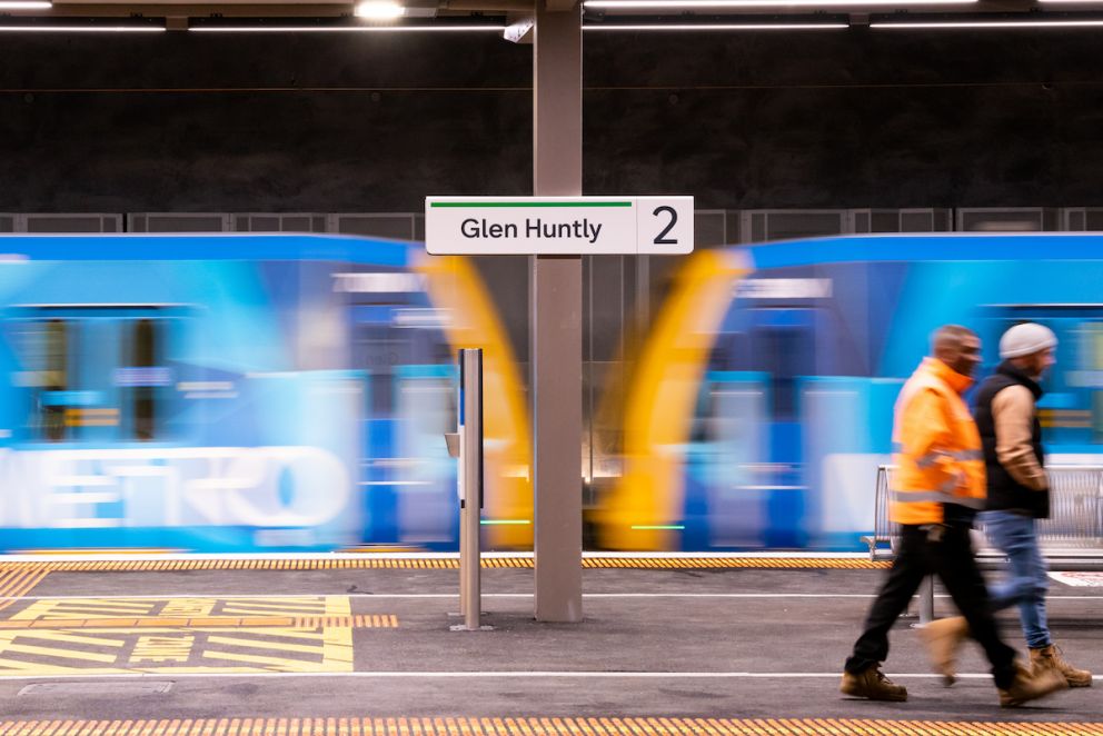 Glen Huntly Station sign with train passing