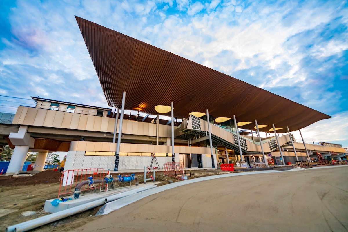 The font of a train station with beige-coloured panels along the front and a modern-looking roof covering it, supported by large metal poles.