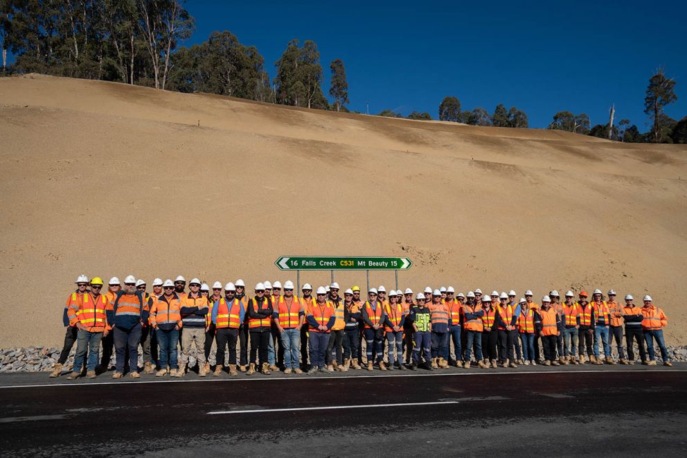 Crews pose together for a picture in front of the landslip before two lanes open on 27 May