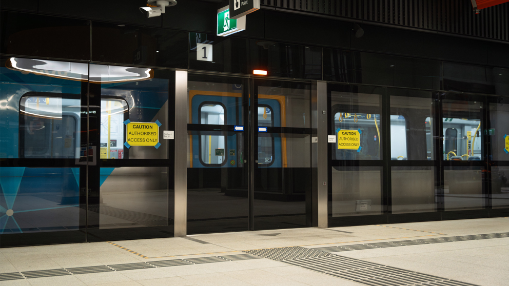 A train at a Metro Tunnel station with open doors and the platform screen doors closed in front
