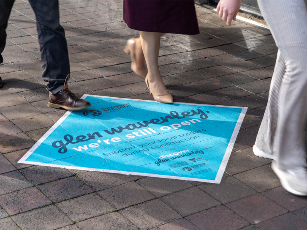 Image shows local community walking across SRL Glen Waverley painted sign.