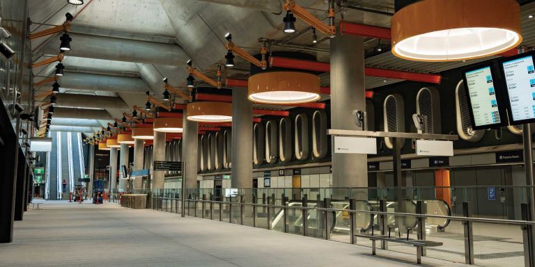 Parkville Station concourse, showing large cylindrical orange lights, passenger information displays, and escalators to ground level. 