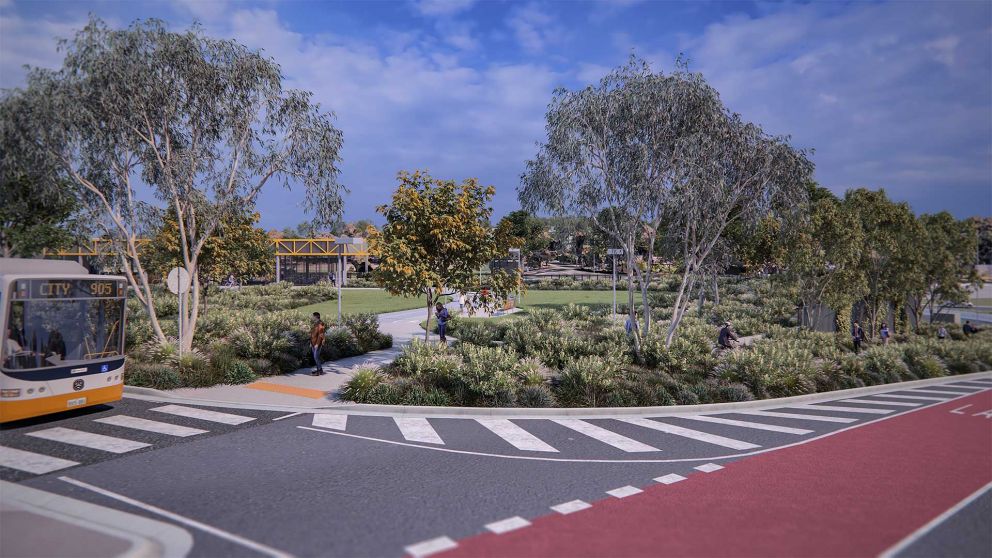 Artist impression of Bulleen Park and Ride looking south east from Thompsons Road. A bus is stopped at a zebra crossing, pedestrians and cyclists are utilising the trails surrounding the landscaped open space and the main entry is in the background.