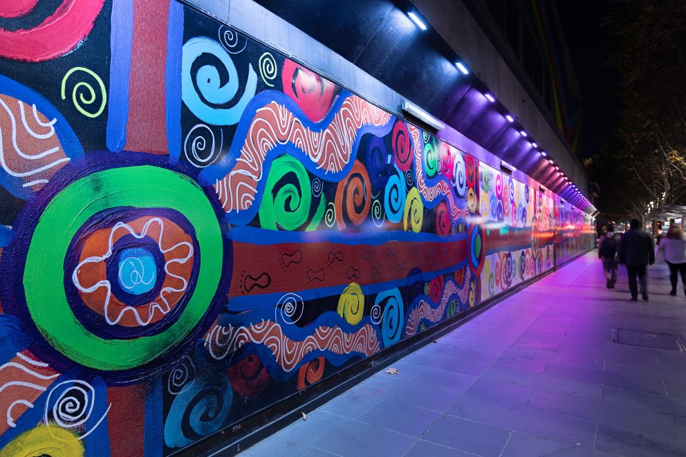A colourful mural lit up at night