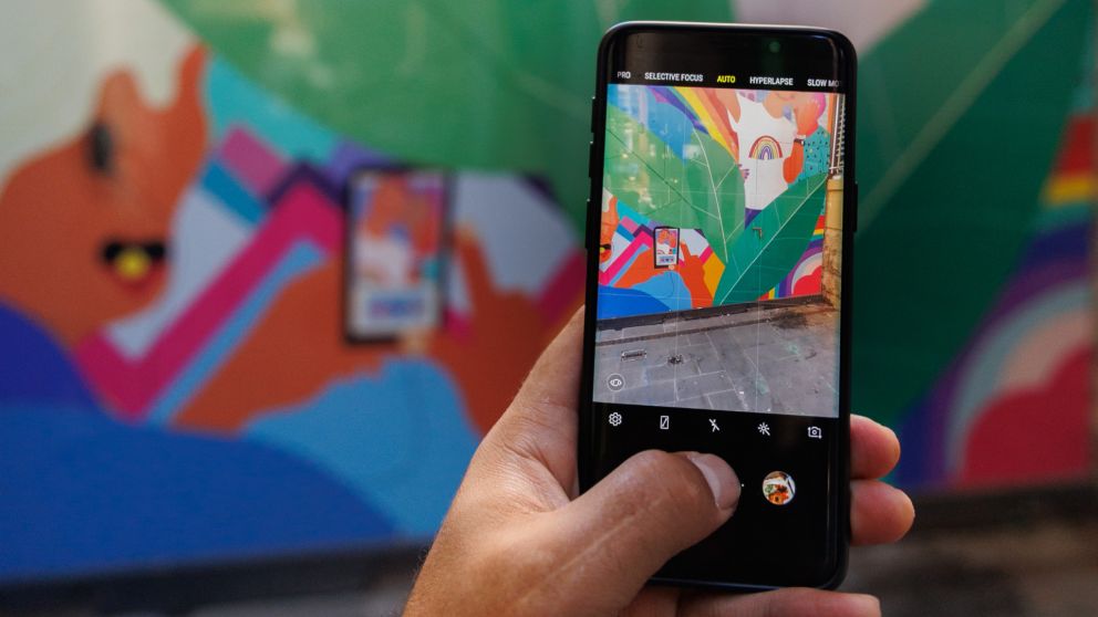 Photo of a hand holding a phone that matches the angle of the phone of the artwork.