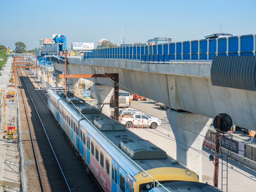 Train on ground level with elevated rail anove.
