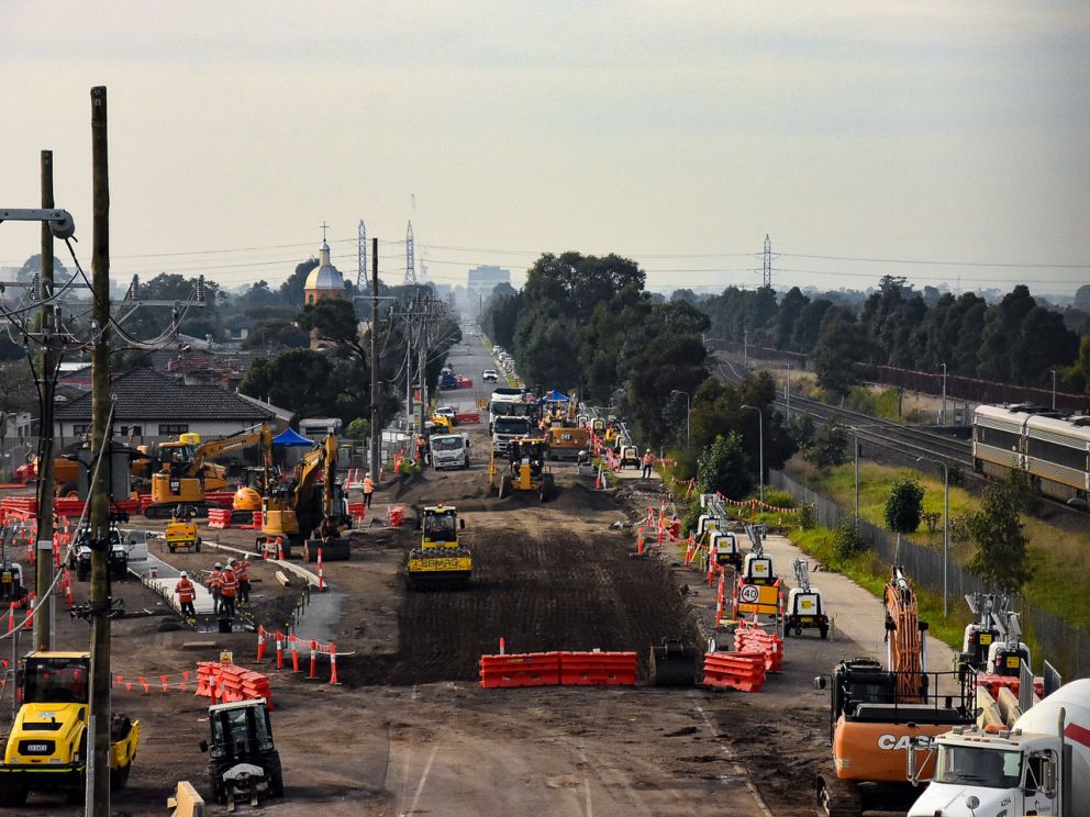 Construction machinery on road alongside rail corridor.