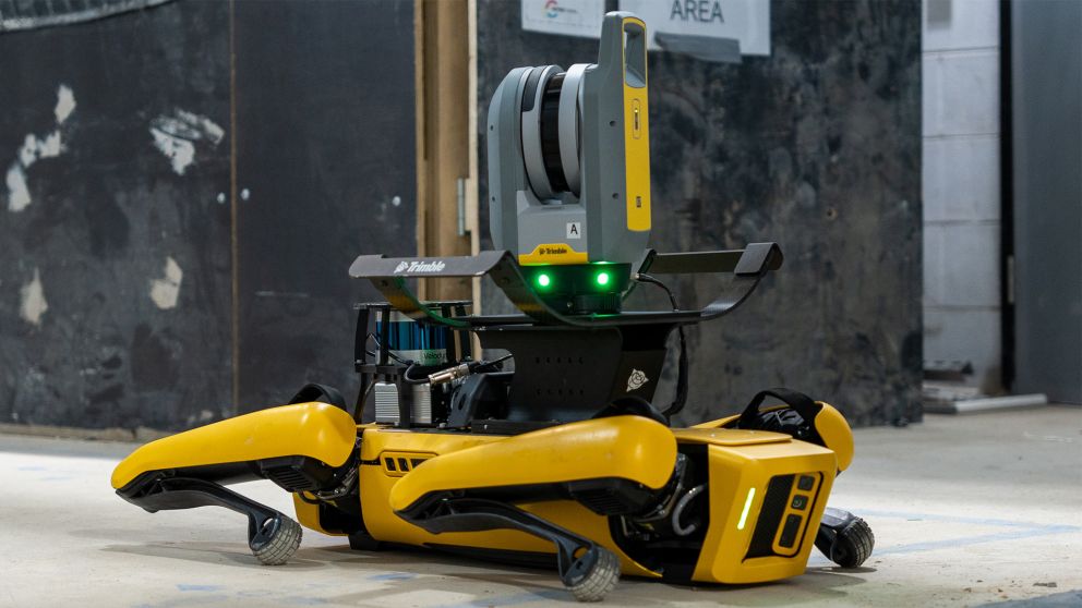 Close up of a yellow and grey robotic dog sitting on the ground