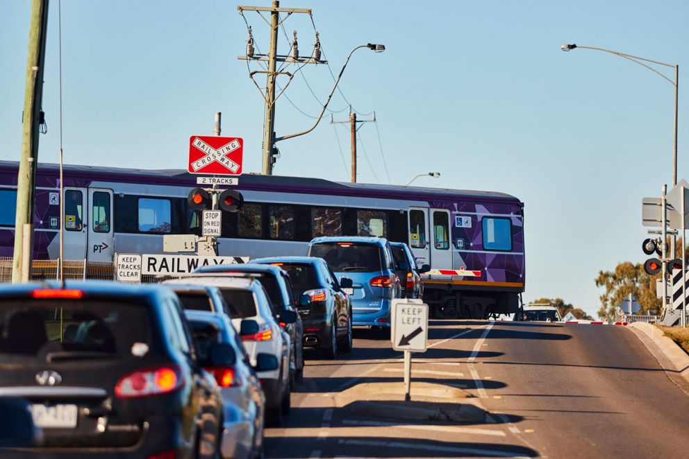 Traffic waiting at the Coburns Road, Melton level crossing as a train is passing through