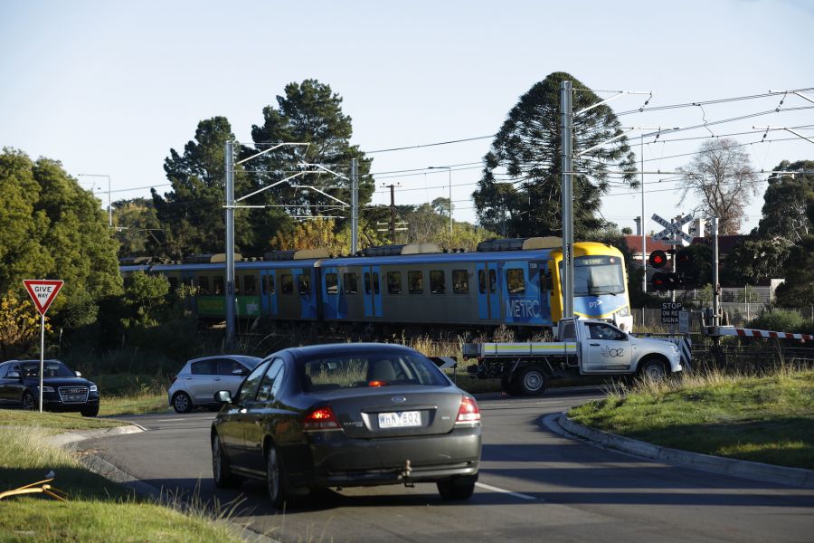 Cars waiting at the boom gates as a train goes past at the Station Street, Beaconsfield level crossing