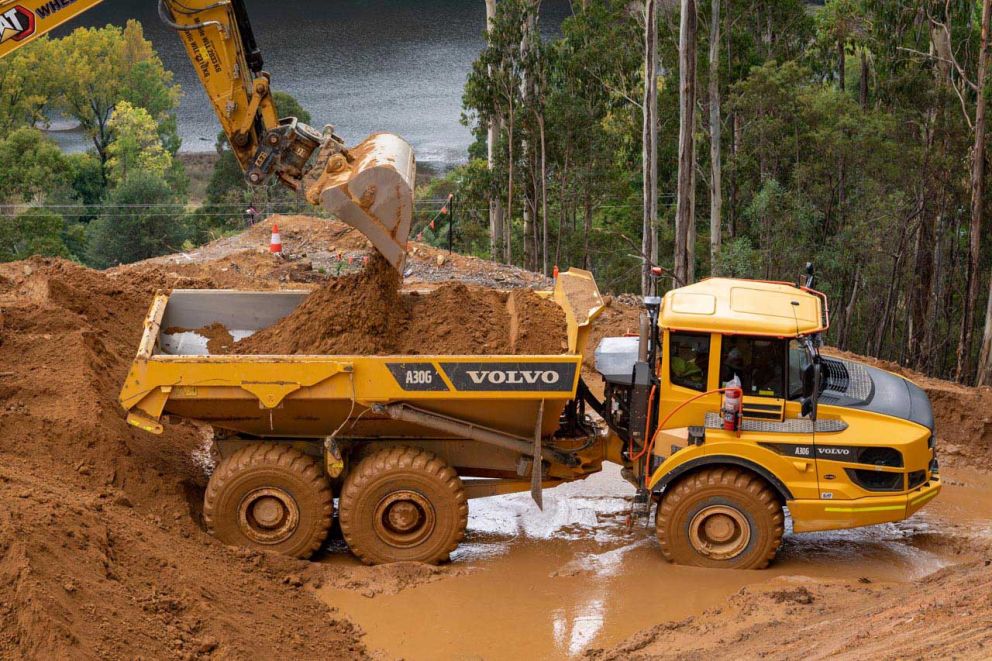 Articulated dump truck is loaded by excavator halfway up the landslip 31 March