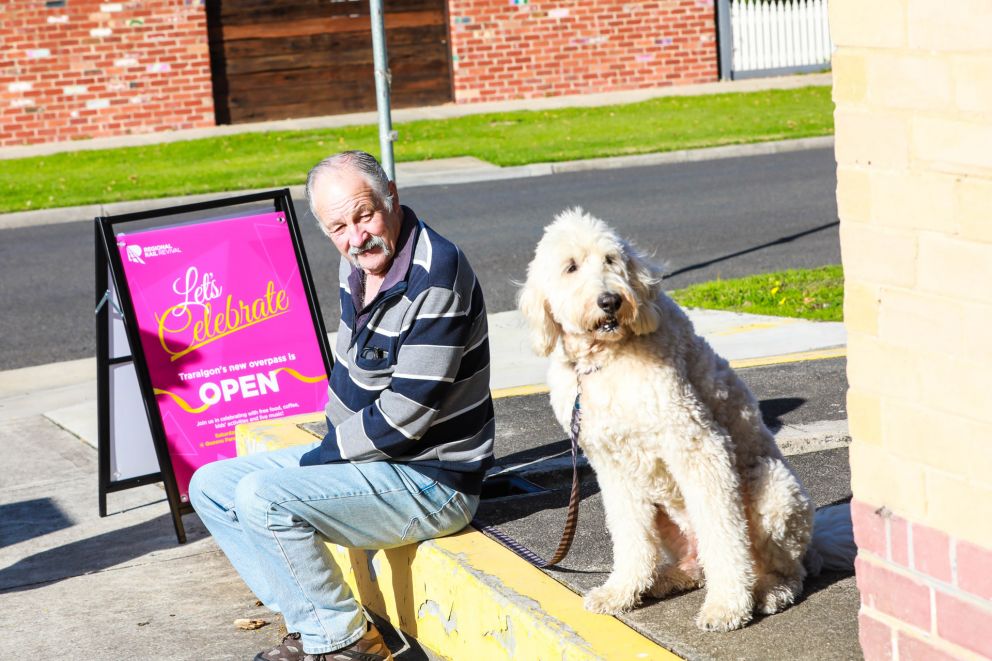 Person sitting with his dog next to an a frame with signage