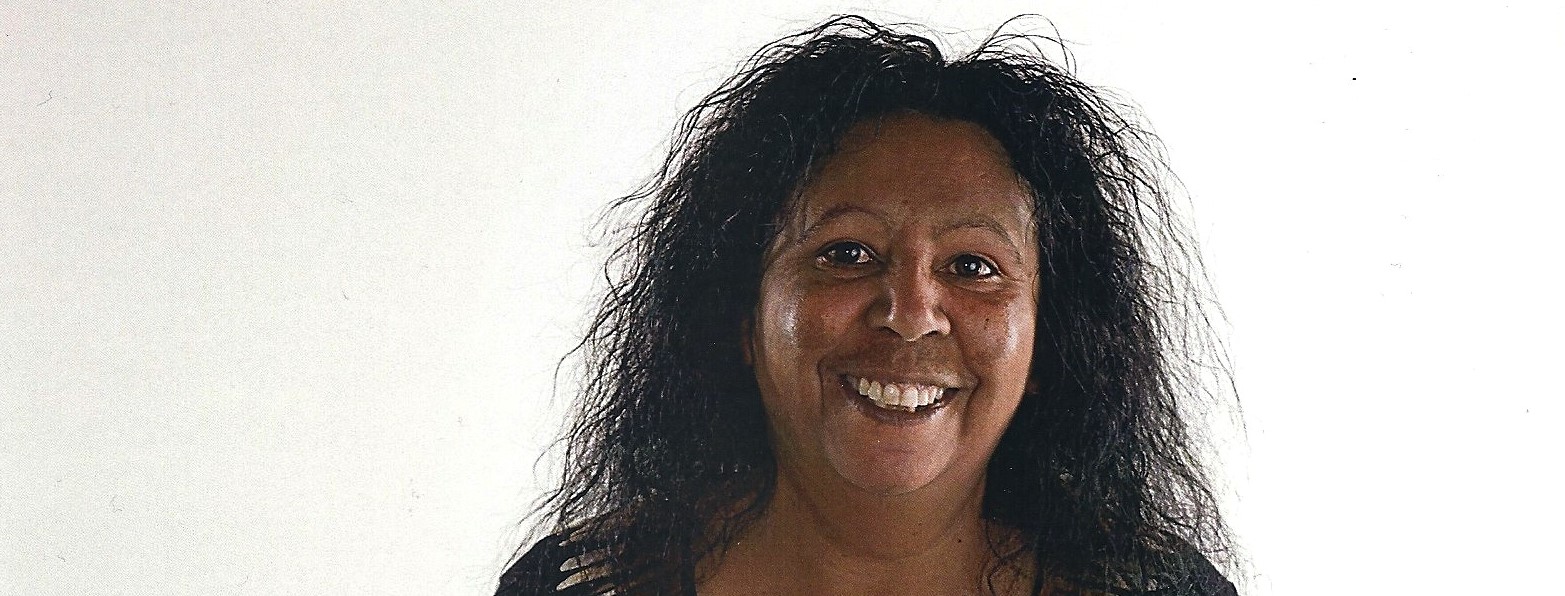 Indigenous woman with long hair smiling wearing a black t-shirt