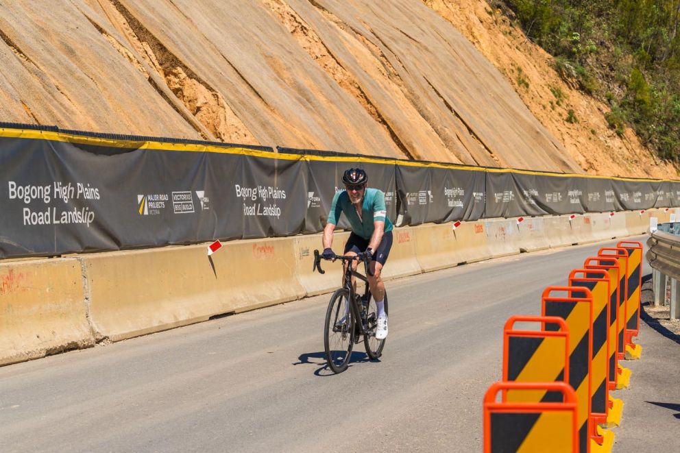 A cyclist navigates his way through traffic management across the face of the landslip