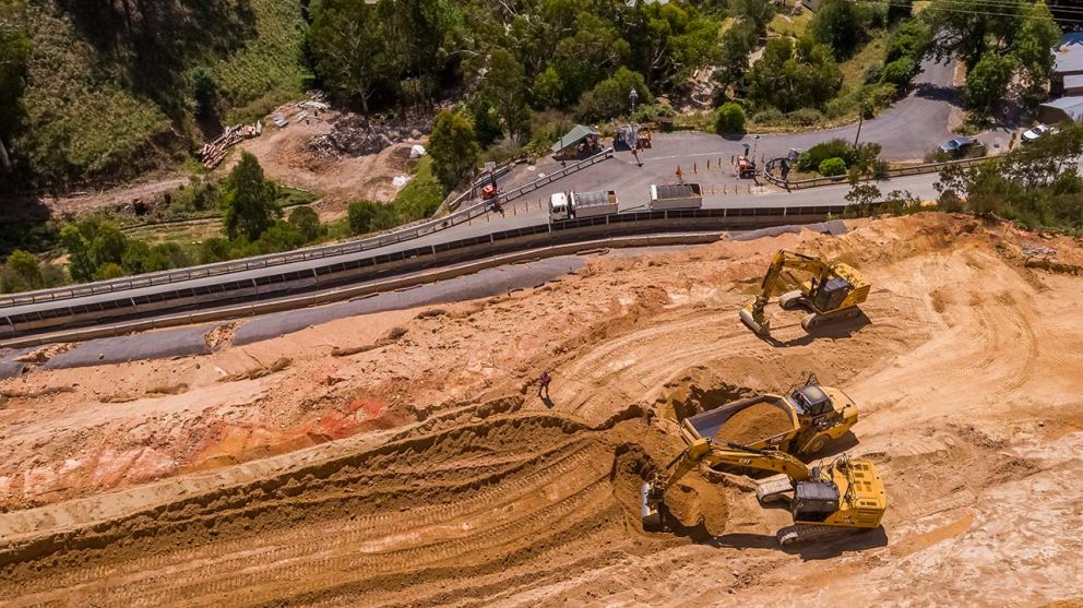 An excavator loads material into a truck on the middle bench of the landslip