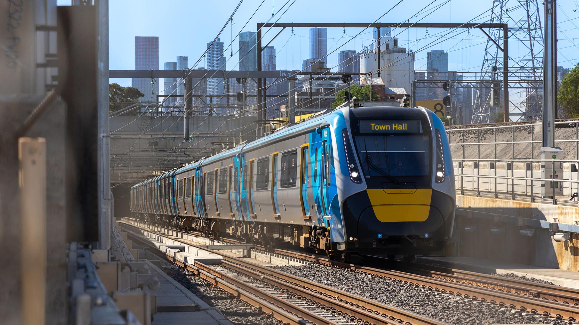 A train with the destination on the front of Town Hall is travelling along train tracks.