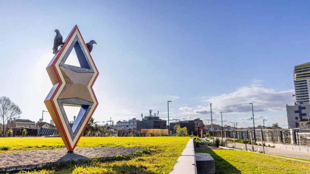 An outdoor sculpture resembling a pointed geometric shape, with two birds sitting on top.